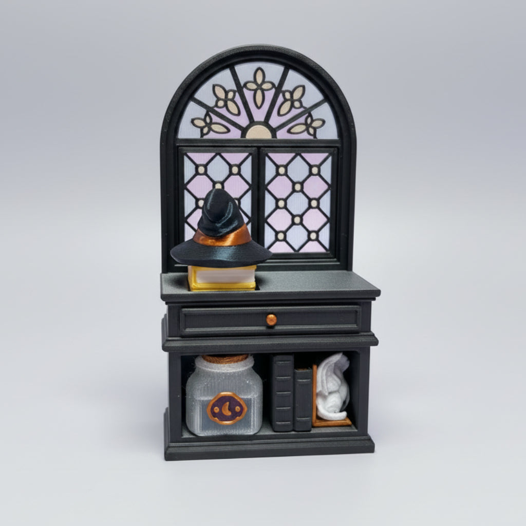 A miniature black witch hut figurine with a stained-glass style arched window, a small black witch hat on top, and tiny shelves with tiny accessories, set on a wooden tabletop.