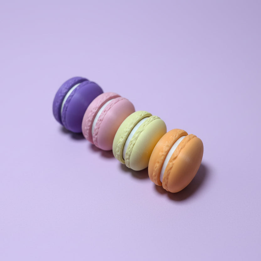 Five colorful macaron cookie fidget clickers on a purple surface