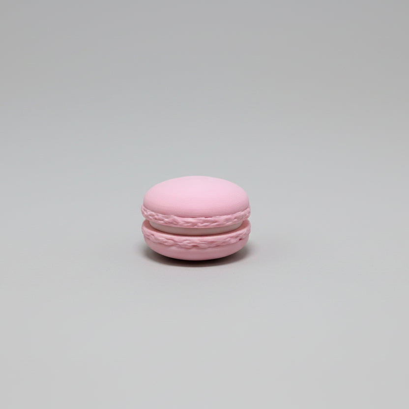 Pink macaron on a wooden surface with a white appliance in the background