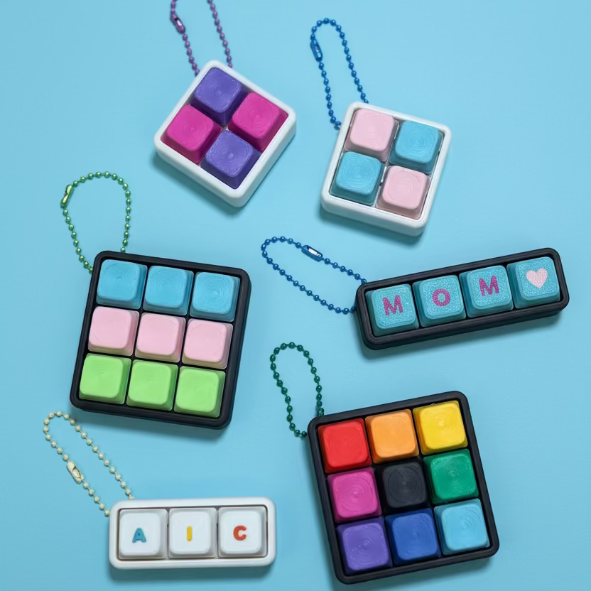 Colorful square keychains with letter and symbol designs on a blue surface