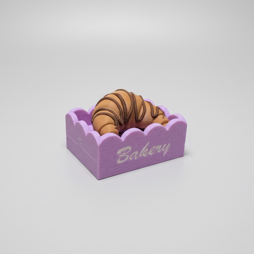 toy croissant in a pink box on a gray background