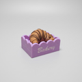 toy croissant in a pink box on a gray background