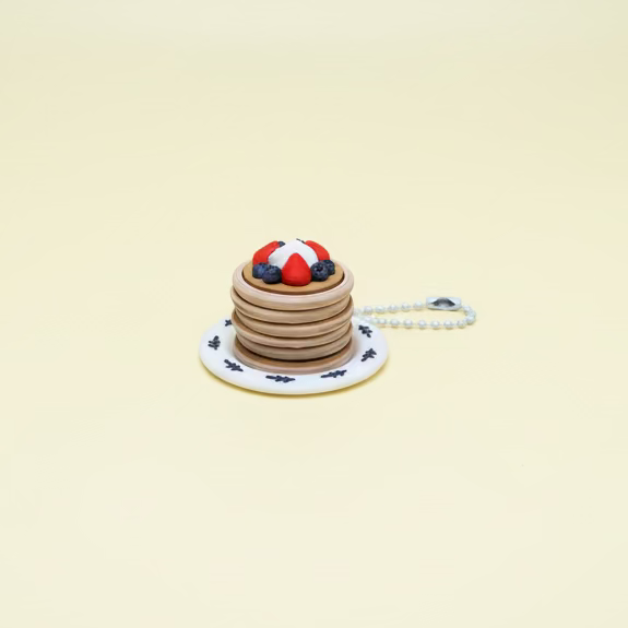 Miniature pancake stack toy with berries on a small plate on a yellow table