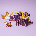 Toy figure of a purple creature with gold and white accents on a purple surface