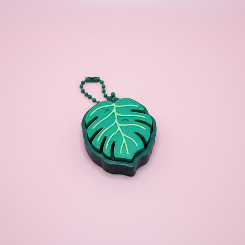 Green leaf-shaped keychain on a wooden surface
