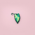 Green leaf-shaped keychain on a pink surface